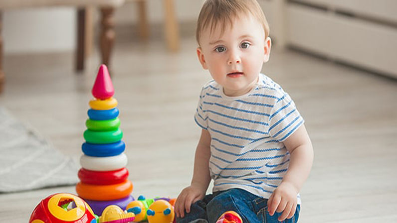 Baby boy is playing with colorful toys
